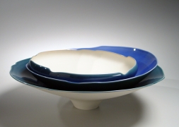 Low round porcelain form of three blue-glazed bowls stacked unevenly inside one another, with center oculus of overlapping bowls, 2012